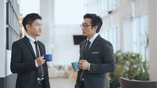2名亚洲华裔白领西装革面，在办公室走廊喝酒休息视频素材模板下载