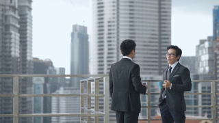 2位亚洲华人白领西装革面，在办公楼阳台上休息聊天视频素材模板下载