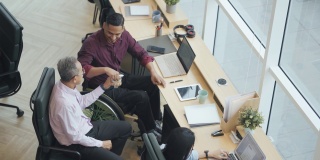 亚洲残疾白领在休息时间与同事一起在办公室吃零食