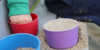 小手认不出来的小男孩小男孩正在玩砂子塑料模具的特写