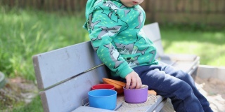 白种人小孩男孩在阳光明媚的日子里在院子外面玩沙盒沙塑料模具