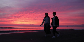 女性朋友在日落时分沿着海滩散步