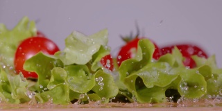 宏观景深:清洁的番茄和长叶莴苣叶落在木制的台面上