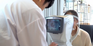 亚洲年轻女子在眼科医生的办公室被专业设备检查她的视力，由电脑监控，准备制作光学眼镜，看后肩