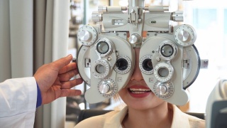 特写:亚洲年轻女子在眼科医生的办公室用专业设备检查她的视力，准备制作光学眼镜视频素材模板下载