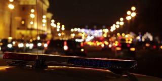 一辆交警车闪烁的灯光和夜间城市街道模糊(散焦)的背景。高清视频