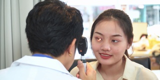 验光师调整视网膜镜和主观屈光的距离，测试亚洲年轻女性的视力，准备配眼镜