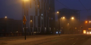 法国斯特拉斯堡——2021年11月6日:雾蒙蒙的秋夜城市，汽车驶过街道，行人和骑自行车的人走在路上