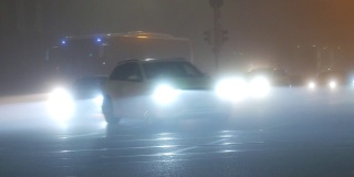 法国斯特拉斯堡——2021年11月6日:雾蒙蒙的秋夜城市，汽车开着前灯和雾灯沿着街道行驶