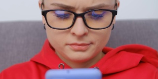 可爱的白色短发女性。假小子戴着眼镜用现代手机拍4k视频。有吸引力的年轻人在智能手机上浏览互联网和社交媒体应用程序