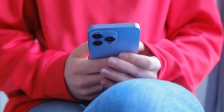 女孩打字在信使应用程序在现代蓝色智能手机与三摄像头。年轻女子使用手机进行在线交流的4k库存视频。女性用手机在线交流
