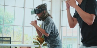 Metaverse，一对年轻夫妇在VR头戴式设备中玩拳击游戏，在家进行虚拟现实踢球训练。