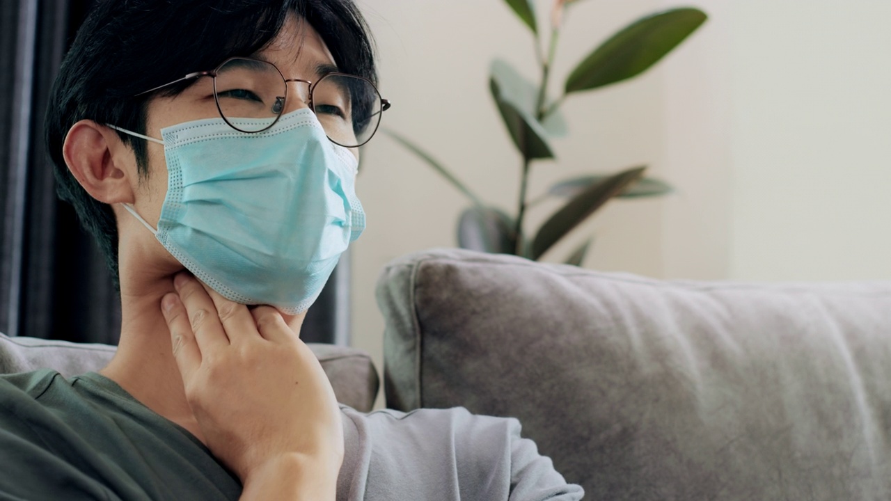 冠状病毒、covid-19和隔离的亚洲病人戴着防护口罩，喉咙痛和咳嗽。社会距离