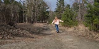 玩乐的时间。小女孩在森林里的小路上奔跑，蹦蹦跳跳，活跃的户外游戏。慢动作