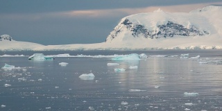 南极洲。南极洲雪山和冰雪海岸的景观。美丽的蓝色冰山与镜面反射漂浮在开放的海洋。严酷大陆上的冰川。