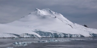南极洲。南极洲雪山和冰雪海岸的景观。美丽的蓝色冰山与镜面反射漂浮在开放的海洋。严酷大陆上的冰川。