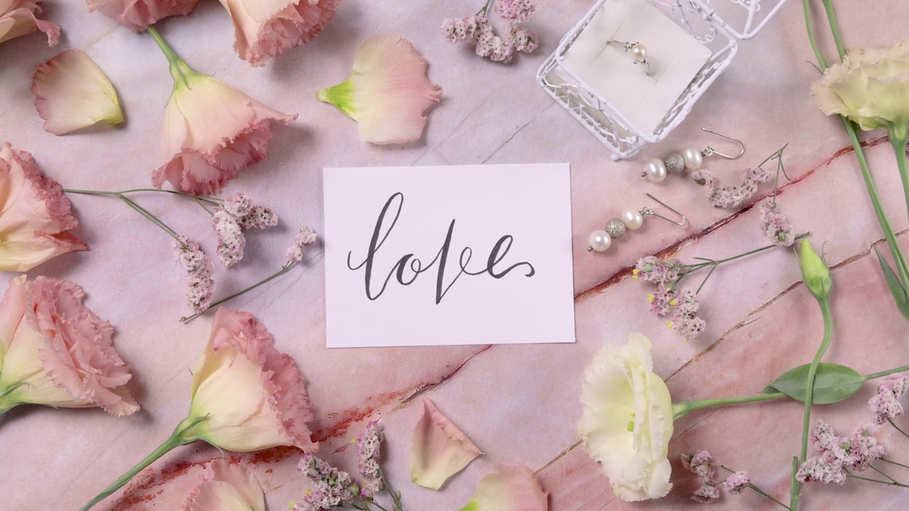 爱情卡片在大理石桌子上近粉红色的花俯视图放大