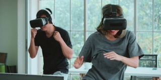 Metaverse，一对年轻夫妇在VR头戴式设备中玩拳击游戏，在家进行虚拟现实踢球训练。
