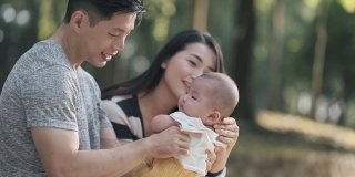 亚洲华人父母周末早上在公园里和他们的孩子亲密无间