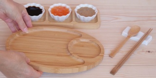 三种酱汁，竹制餐具和一个木盘。