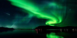 壮丽的绿色极光在山上星空背景下与镜子反射在湖面上。4 k