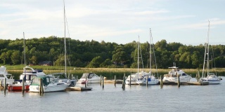 许多游艇在小的乡村边码头，从河边看靴子，在瑞典旅行