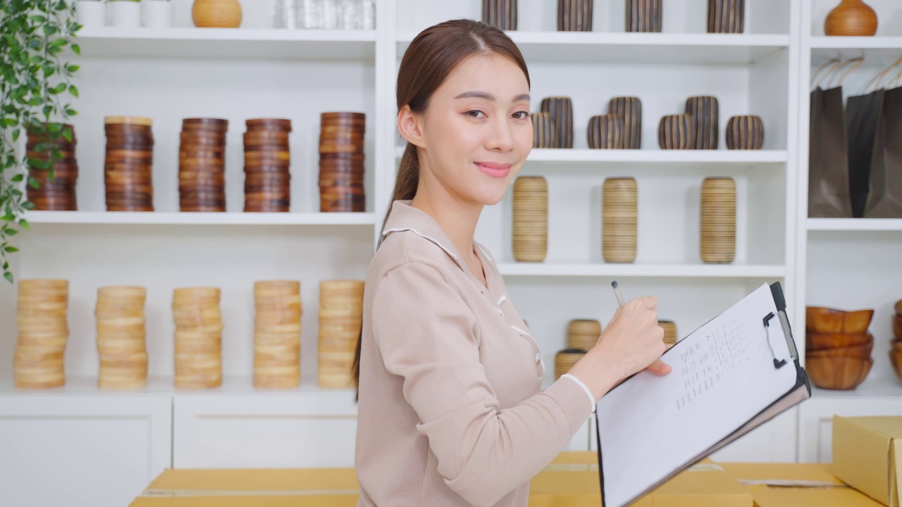 亚洲女商人肖像检查花瓶订单和看相机。年轻有吸引力的商业女孩工作准备包裹盒子检查电子商务航运在线零售销售在家里的商店。