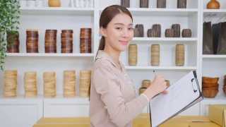 亚洲女商人肖像检查花瓶订单和看相机。年轻有吸引力的商业女孩工作准备包裹盒子检查电子商务航运在线零售销售在家里的商店。视频素材模板下载