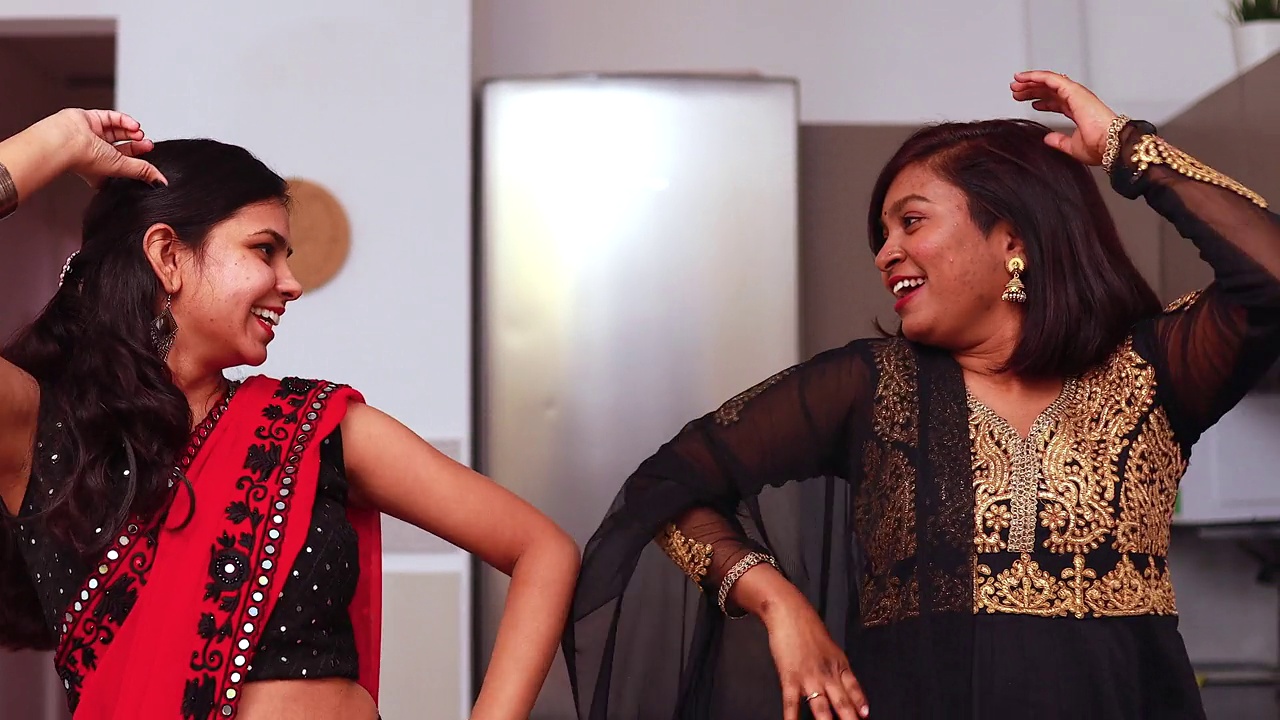 两个美丽的印度快乐姐妹在家里的客厅里跳舞