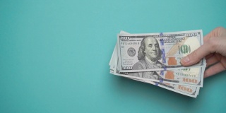 一个商人的手递过一叠蓝色背景的美元。