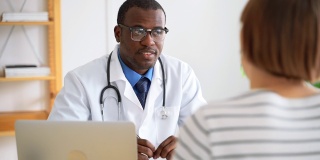医生在医院为病人咨询健康状况。非洲黑人男性医生与女性交谈