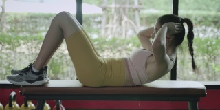 健身理念，美丽的亚洲女孩穿着运动服在健身房里做仰卧起坐。在健身训练中加强自己的腹部核心肌肉。健康的生活方式