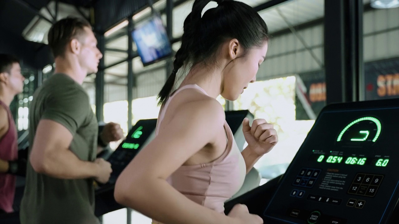 健康的年轻亚洲女性正在跑步机上跑步。