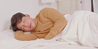 英俊迷人的亚洲男人睡觉和甜蜜的梦躺在床上舒适的卧室早上感觉如此放松和舒适。健康的年轻男性在家就寝。医疗保健的概念