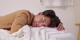 英俊迷人的亚洲男人睡觉和甜蜜的梦躺在床上舒适的卧室早上感觉如此放松和舒适。健康的年轻男性在家就寝。医疗保健的概念