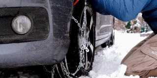 困在雪中的汽车和在轮胎上装雪链的人