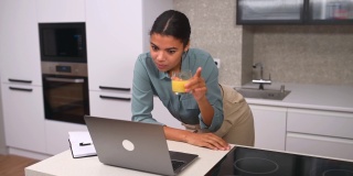 快乐年轻漂亮的女人看着笔记本电脑屏幕，举行视频电话会议谈话
