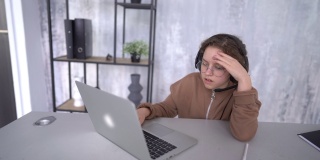 在远程学习时，一个戴着耳机看着笔记本电脑屏幕的女孩的脸。一个女生在网上上课
