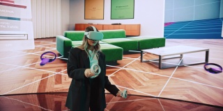 室内设计师展示现代VR软件设计生活空间。女工程师使用耳机和控制器在舞台上的大屏幕上展示功能。