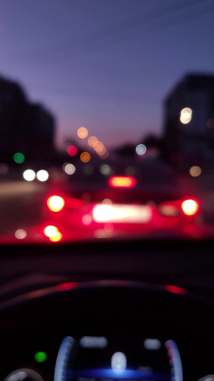 街灯和五颜六色的交通灯从汽车。夜模糊散景摘要。城市大气的心情。垂直视频素材进尺