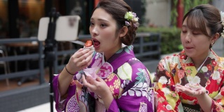 穿着和服的年轻女性朋友为了拍视频而吃街头小吃