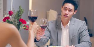 亚洲年轻情侣共进晚餐庆祝情人节。吸引人的浪漫新婚男女享受夜晚派对，在结婚纪念日在家碰杯喝酒
