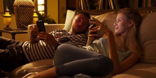 情侣们呆在舒适舒适的房间里，一起无聊。专注于智能手机