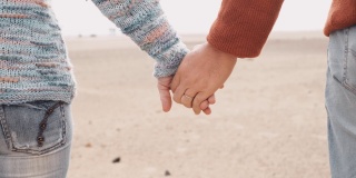 近距离的成人夫妇牵手，用爱和温柔抚摸。生活的甜蜜概念与浪漫的人在接触。户外沙滩旅行背景为男女生活方式