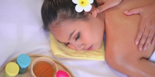 深色皮肤的亚洲妇女正在接受油按摩她的背肩区域在泰国温泉，顶视图。