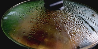 水从锅的玻璃盖上滴下来。烹饪