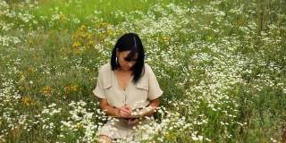 女人们用钢笔或绘画，在笔记本上书写鲜花盛开的草甸