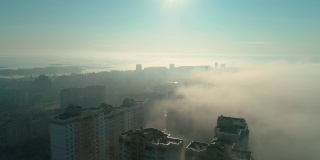 黎明时分，无人机在雾中飞过城市上空的镜头