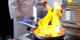 特写镜头。专业厨师用火焰烹饪海鲜。用火烹饪一道菜。厨师在厨房里把食物扔到煤气炉的火上做饭。高级餐厅的美食