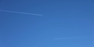 两架喷气式飞机在高空互相飞行，在清澈的蓝天上留下了尾迹。